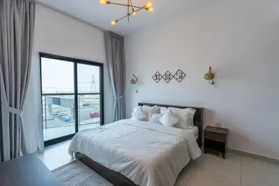 a bedroom with a white bed with a large window at 1 Bedroom in JVC in Dubai