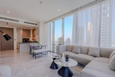 a living room with a couch and tables and a kitchen at TRPS - Peninsula Five, Business Bay - Stylish 1BR - Canal & Burj Khalifa Views in Dubai