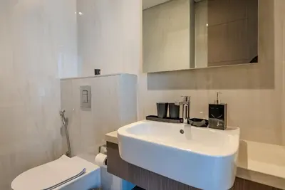 a bathroom with a white sink and a toilet at TRPS - Peninsula Five, Business Bay - Stylish 1BR - Canal & Burj Khalifa Views in Dubai