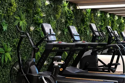 a row of exercise bikes in front of a green wall at Spacious 1 BHK with City Views Near Burj Khalifa in Dubai