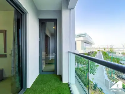 a balcony with a door and green grass at Modern 2B Apartment with Pool Acess SOBHA CREEK in Dubai