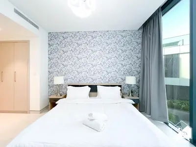 a bedroom with a large white bed with two lamps at Modern 2B Apartment with Pool Acess SOBHA CREEK in Dubai