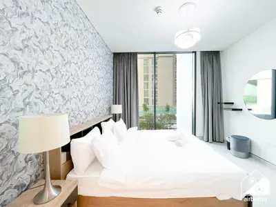 a bedroom with a white bed and a window at Modern 2B Apartment with Pool Acess SOBHA CREEK in Dubai