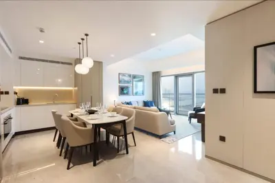 a dining room and living room with a table and chairs at Livbnb - Premium 3BR with Burj Skyline View in Dubai
