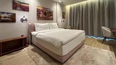 a bedroom with a large white bed and a desk at Bespoke Holiday Homes - Cozy 1BR Retreat in Haven Residences JVC in Dubai