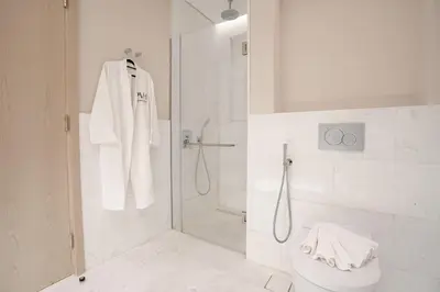 a white bathroom with a shower and a toilet at PVH - Palm Tower - Inviting Studio with Sea View in Dubai