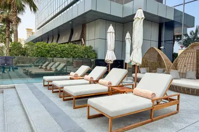 a row of lounge chairs and umbrellas in front of a building at PVH - Palm Tower - Inviting Studio with Sea View in Dubai
