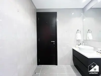 a black door in a white bathroom with a sink at Luxury 2BR in Merano Tower Panoramic City Views in Dubai