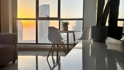 a living room with a table and chairs in front of a window at Golden Hour Stay Sea View in Marina Dubai in Dubai
