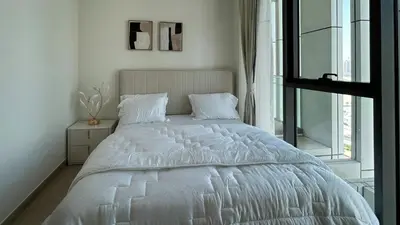 a white bed in a white bedroom with a window at Bespoke Holiday Homes - 1BR Apartment with Creek View in Al Jaddaf in Dubai