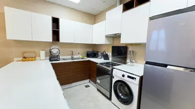 a kitchen with white cabinets and a washer at Joya Verde Residence - 1BHK Huge Apartment in Dubai