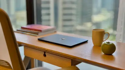 a desk with a laptop and a cup and books at Majestic ActOne 1BR dowtown Dubai in Dubai