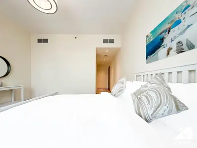 a white bedroom with a large white bed with pillows at Stunning 2-Bedroom Apartment with Canal Views in Dubai