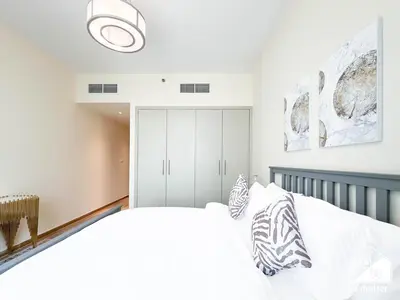 a bedroom with a white bed and a white cabinet at Wonderful 2B with Canal Views at Amna Tower in Dubai