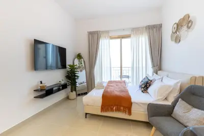 a bedroom with a bed and a tv and a couch at Serene studio apartment with Burj Khalifa view in Jumairah Village Circle JVC in Dubai