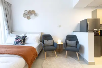 a hotel room with a bed and two chairs at Serene studio apartment with Burj Khalifa view in Jumairah Village Circle JVC in Dubai