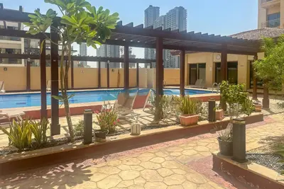 a building with a swimming pool with trees and plants at Serene studio apartment with Burj Khalifa view in Jumairah Village Circle JVC in Dubai