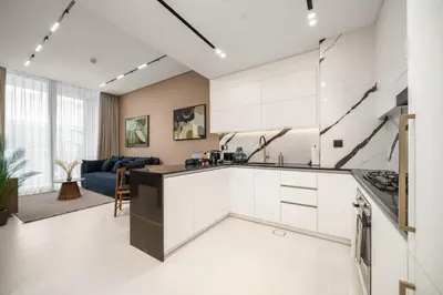 a kitchen with white cabinets and a living room at Trillionaire Bayhouse - Chic 1BR with Views, Pool and Gym in Dubai