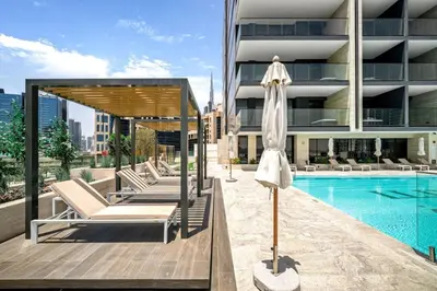 a pool with chairs and an umbrella next to a building at Trillionaire Bayhouse - Chic 1BR with Views, Pool and Gym in Dubai