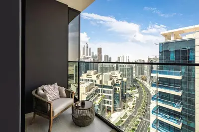a balcony with a chair and a view of a city at Trillionaire Bayhouse - Chic 1BR with Views, Pool and Gym in Dubai
