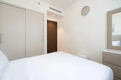 a bedroom with a white bed and a clock on the wall at Lux 1 Bed room partment in Sobha Creek Vistas Reserve tower at 9th floor in Dubai