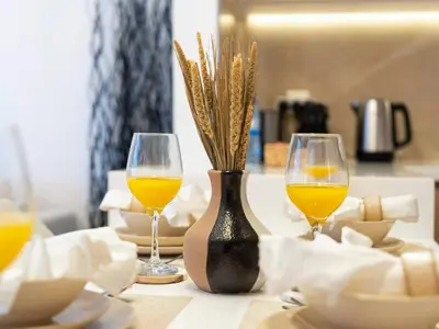 a table with two wine glasses and a vase with flowers at Brand New Luxurious 2 Bed in JVC with Padel Court in Dubai