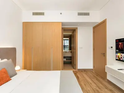 a bedroom with a white bed and a flat screen tv at Brand New Luxury 2 Bedroom with Padel Gym Pool Cinema in Dubai