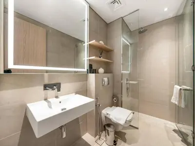 a bathroom with a sink and a toilet and a mirror at Brand New Luxury 2 Bedroom with Padel Gym Pool Cinema in Dubai