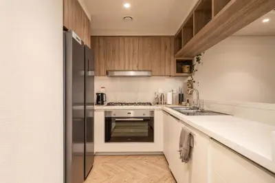 a kitchen with a stainless steel refrigerator and wooden cabinets at Seraya Residence 3 - 4BDR - Burj Views - Amenities and Concierge in Dubai
