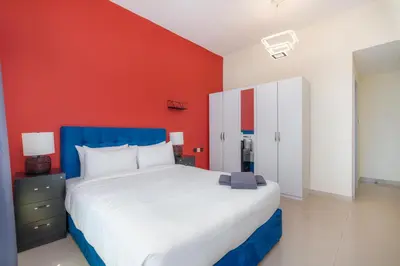 a bedroom with a white bed and a red wall at White Sage High Floor 1BR Metro Access JLT in Dubai
