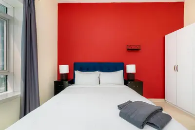 a bedroom with a red wall and a bed at White Sage High Floor 1BR Metro Access JLT in Dubai