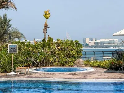 a swimming pool with a view of the water at Tiara Residence, The Palm - Elegant 1BR with Full Sea View in Dubai