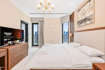 a bedroom with a large bed and a flat screen tv at Cozy & Spacious 2 BHK Downtown in Dubai