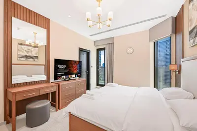 a bedroom with two beds and a desk and a television at Cozy & Spacious 2 BHK Downtown in Dubai