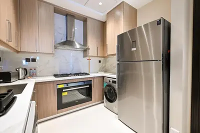 a kitchen with a stainless steel refrigerator and wooden cabinets at Cozy & Spacious 2 BHK Downtown in Dubai