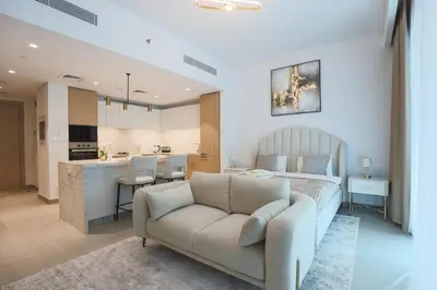 a living room with a couch and a kitchen at Stylish Studio at Berkeley Place by Ellington in Dubai