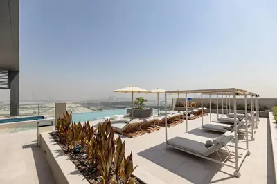 a row of lounge chairs and umbrellas next to a swimming pool at Stylish Studio at Berkeley Place by Ellington in Dubai