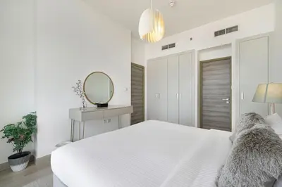 a white bedroom with a large bed and a mirror at Luxury One-Bedroom Apartment in Bloom Heights in Dubai