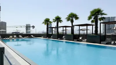 a swimming pool on top of a building with palm trees at Luxury One-Bedroom Apartment in Bloom Heights in Dubai