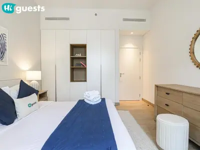 a bedroom with a large bed and a dresser at HiGuests - Breezy 1 BR Retreat Near La Mer Beach in Dubai