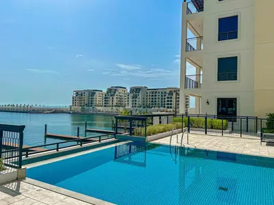 a large blue swimming pool next to a building at HiGuests - Breezy 1 BR Retreat Near La Mer Beach in Dubai