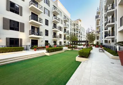 a courtyard of an apartment building with a green lawn at Goldbest Beachfront 2BR La Mer in Dubai