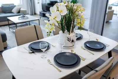 a table with plates and glasses and a vase of flowers at Goldbest Beachfront 2BR La Mer in Dubai