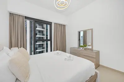a white bedroom with a large white bed and a mirror at Majestic Act2 1BR Dowtown Dubai in Dubai