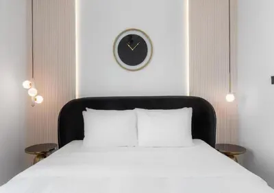 a bed with a black headboard and a clock on the wall at Novity Signature Homes in Dubai