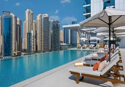 a swimming pool with lounge chairs and a city skyline at Novity Signature Homes in Dubai
