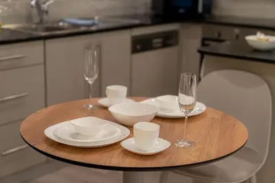 a wooden table with wine glasses and plates on it at Trendy & Cozy Getaway in Dubai