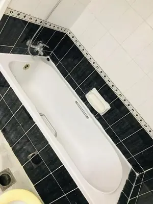 a white tub in a bathroom with a black tiled floor at hostel in Dubai