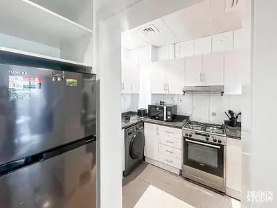 a kitchen with white cabinets and a stainless steel refrigerator at DREAM by Design Studio in Dubai