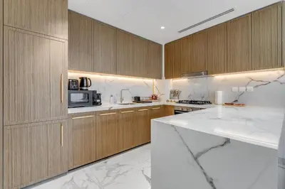 a kitchen with wooden cabinets and a white counter top at GLOBALSTAY Azizi Riviera 59 in Dubai